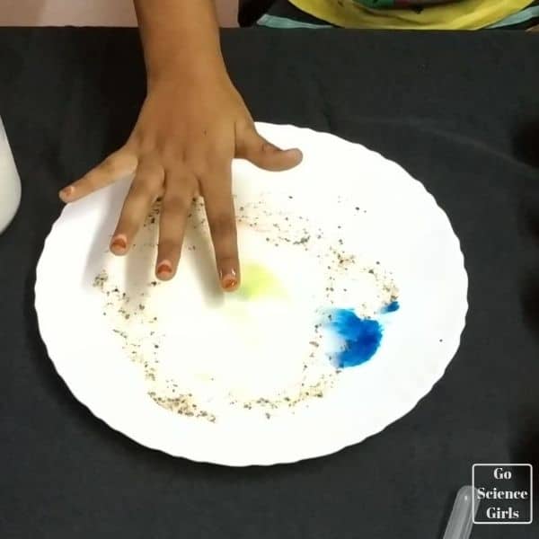 fingers near to milk solution - milk swirl experiment for kids