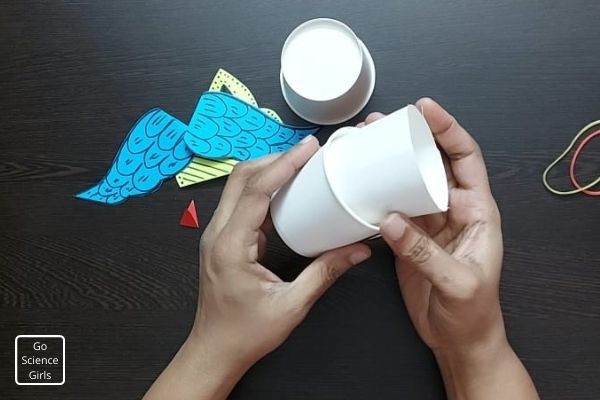 insert the cut paper cup into another one to make the rocket thick